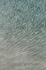 Calm clear water gently ripples over sandy beach at midday in a tropical paradise setting
