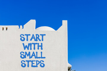 Start with small steps symbol. Concept words phrase Start with small steps on beautiful white wall. Beautiful white wall and blue sky background. Business Start with small steps concept. Copy space.