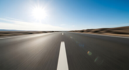 A sun-drenched highway stretches towards a bright horizon under a clear blue sky.