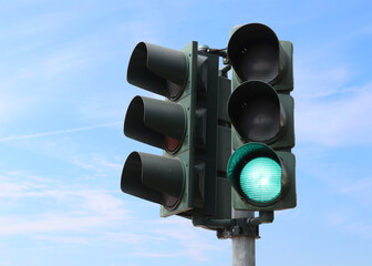 Green traffic light with the sky as background.