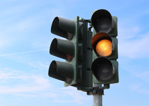 Yellow traffic light with the sky as background.