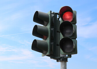 Red traffic light with the sky as background.