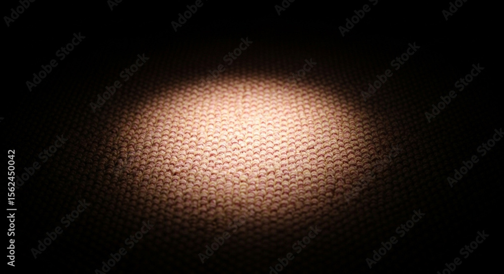 Poster close up of textured fabric with a spotlight creating a warm glow and dark shadows