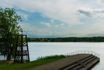 Scenic view of a tranquil lake with a wooden observation tower and stepped dock in the foreground....
