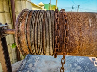 A rusty chain is wrapped around a metal pipe. The chain is old and rusted, and the pipe is also old...