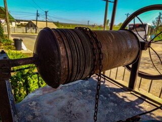 A chain is wrapped around a metal pipe. The chain is rusty and the pipe is old. The scene is set in...