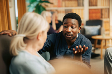 Young male healthcare worker communicating with elderly woman at old age home