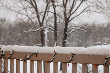 Snowy Deck Railing Adorned with Christmas Lights During Winter