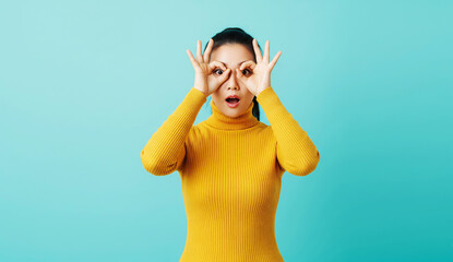 Playful Woman in Yellow Sweater Looking Through Hand Binoculars