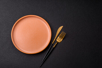 Empty round black plate for food, kitchen utensils on dining table. Empty plate