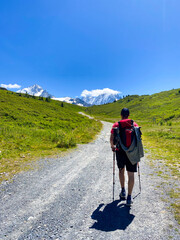 Solo Hiker Walking Toward Snow-Capped Mountains on a Sunny TMB (Tour du Mont Blanc) Trail. Vertical