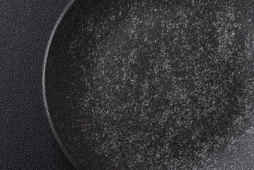 Empty round black plate for food, kitchen utensils on dining table. Empty plate