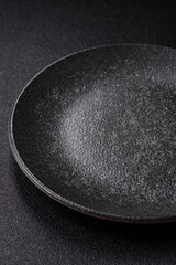 Empty round black plate for food, kitchen utensils on dining table. Empty plate