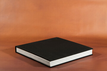 Black Hardcover Book on Brown Surface
