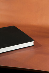 Black Hardcover Book on Brown Surface
