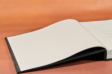 Black Hardcover Book on Brown Surface
