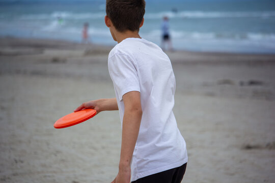 Teen boy readies frisbee throw on seaside beach