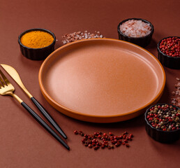 Empty round black plate for food, kitchen utensils on dining table. Empty plate