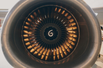 Detailed close-up of airplane jet engine turbine showing metallic blades and fan structure,...