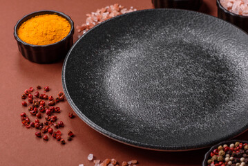 Empty round black plate for food, kitchen utensils on dining table. Empty plate