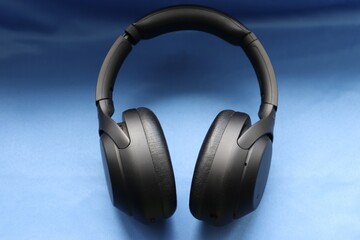modern black wireless headphones on a blue background as a symbol of mobility and technological choice