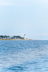 Lighthouse and Coastline Seen Through Sailboat Rigging
