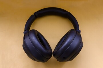 modern black wireless headphones on a yellow background as a symbol of mobility and technological choice