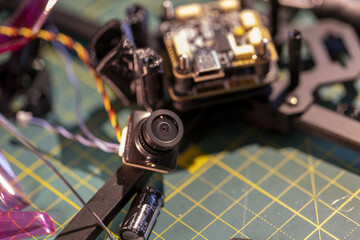 Close-up view of FPV drone camera and circuit board on workbench