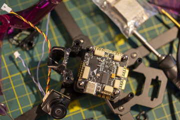 Building components of 5-inch FPV drone on workbench with microchip and frame parts.