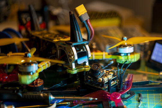 Yellow propeller 5-inch FPV drone with visible circuit components on cluttered workspace table - Powered by Adobe
