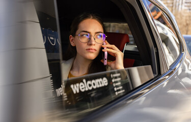 Woman in car talking on smartphone with focused expression