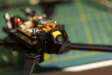 Close-up view of small FPV drone camera and components on workbench