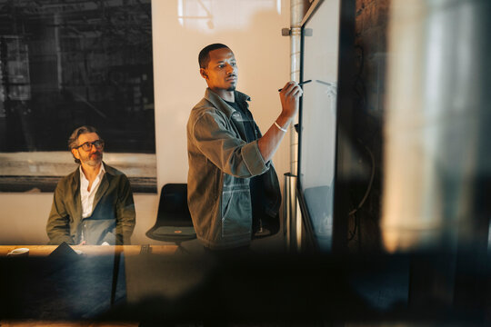 Male entrepreneur writing ideas on screen in meeting at office