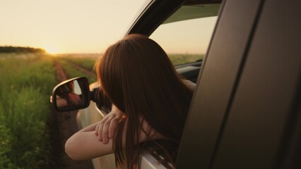 Young woman travels looks out of car window. Road trip on way to vacation. Student on vacation enjoys nature from car window, vacations, adventures, sun. Happy moments, road to sun. Family on vacation