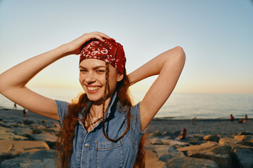 smiling woman in modern boho-western denim street style wearing a red bandana outdoors at sunset...