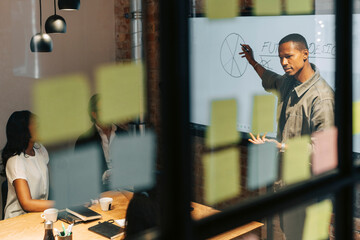 Businessman explaining diagram to team attending meeting in conference room at office