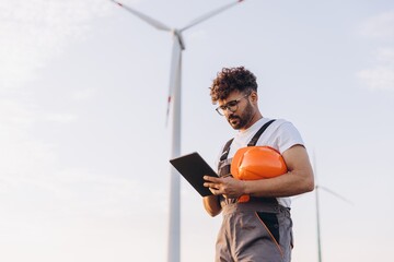 Technician working on a tablet next to a wind turbine