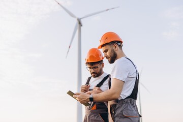 Engineers using tablet working on wind turbine for sustainable energy
