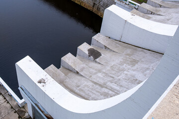 Top view of curved concrete steps of a hydro dam structure leading to water. Modern civil...