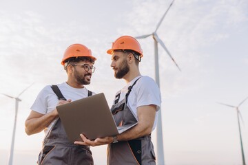Arab engineers discussing about wind turbine maintenance using laptop