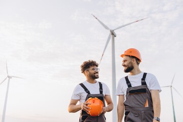 Arabian engineers discussing renewable energy near wind turbines