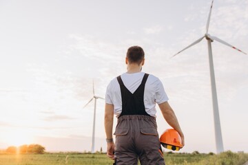 Engineer looking at wind turbines in a field at sunset
