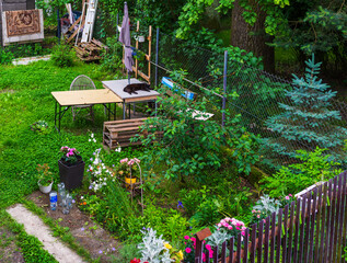 A vibrant garden filled with blooming flowers, wooden pallets, and a relaxed black cat lying on a...