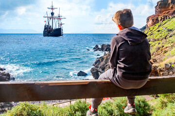 teenager traveler, boy 10-12 years old looking sailing ship, galleon at sea, peaceful mountain...