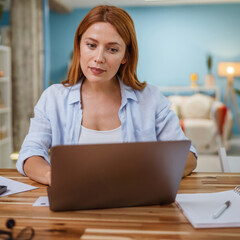 Confident adult woman work from home on laptop in the living room