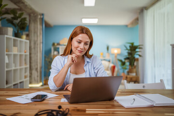 Confident adult woman work from home on laptop in the living room