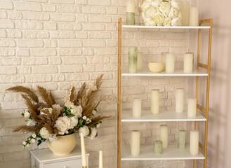 Wedding interior of room. On shelf lies a white bouquet of bride flowers, candles, glasses and...