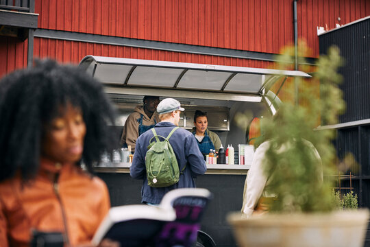 Food truck owners taking order of customers at sunny day