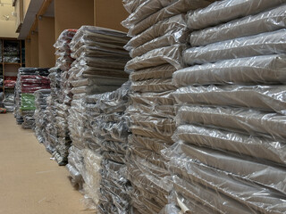 Stacked plastic-wrapped clothing items in a retail storage area, showcasing organized inventory and...