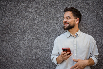 Handsome stylish caucasian man use mobile phone in front grey wall